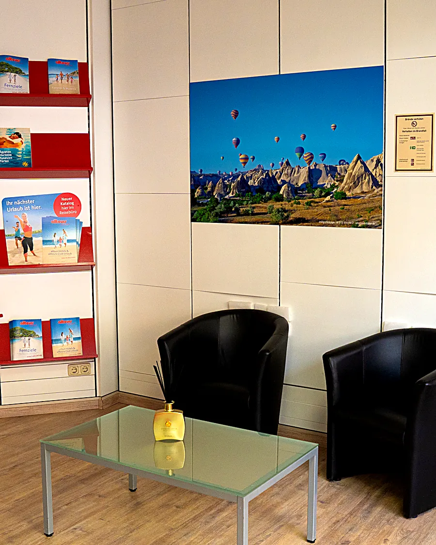 Sitzecke im Reisebüro Bahar mit gerahmten Reisezielen an der Wand
